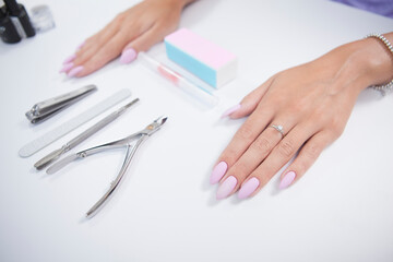 Beautiful female hands with pink manicure on nail salon table