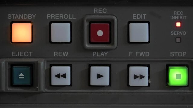 Close up of the control panel of an old broadcasting recorder where we can see the play buttons while a person presses the play button