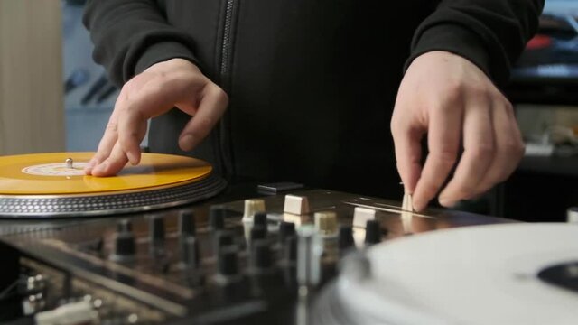 Hip hop dj scratches vinyl records in slow motion video clip. Professional disc jockey mixing tracks on party with retro turntables and sound mixer