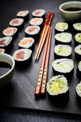 Close-up of a slate of fish sushi and vegetable sushi next to chopsticks. Oriental food