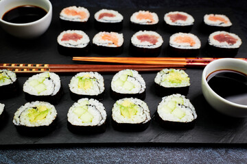 Presentation on a slate of seafood sushi and vegetable sushi with chopsticks. Oriental food