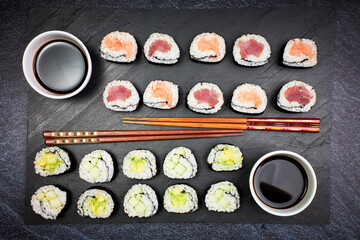 Presentation on a slate of seafood sushi and vegetable sushi with chopsticks. Oriental food
