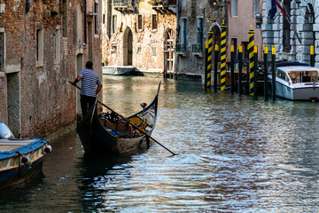 Fototapeta na wymiar Venetian gondolier, rowing a traditional gondola through the green canals of Venice, Italy