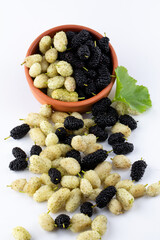 Three organic Mulberry fruits with green leaves isolated on white background.