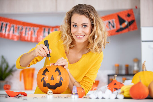 woman artist prepares for halloween and paints pumpkins