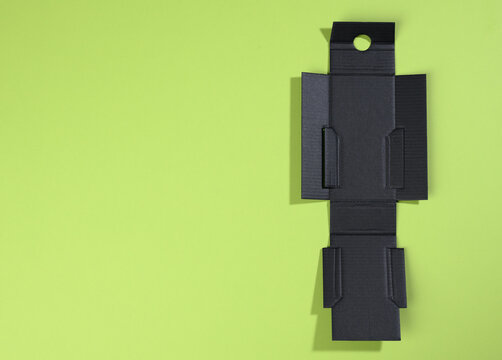 collapsible inner protective black box made of corrugated cardboard for packages with breakable goods on a green background, for perfumery