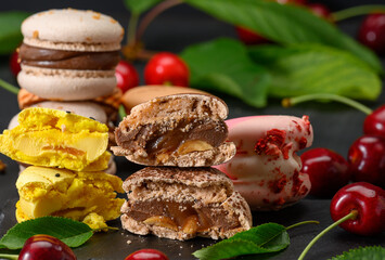 stack of multicolored macarons and ripe red cherries on blue wooden background