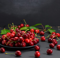 ripe red cherries in a ceramic plate on a black wooden table