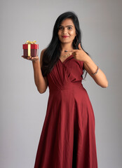 Portrait of a pretty girl holding and posing with gift box on grey background