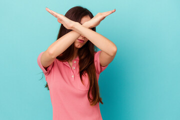 Young caucasian woman isolated on blue background keeping two arms crossed, denial concept.