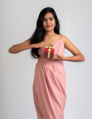 Portrait of a pretty young girl posing with gift box on grey background.