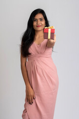 Portrait of a pretty young girl posing with gift box on grey background.