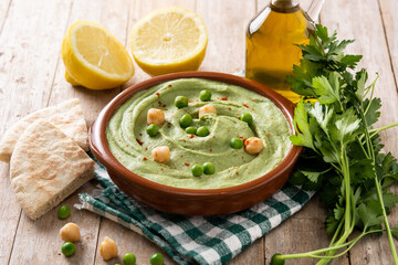 Green pea hummus and pita bread on wooden table