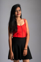 Naklejka premium Young beautiful smiling girl in red and black outfit posing on grey background.