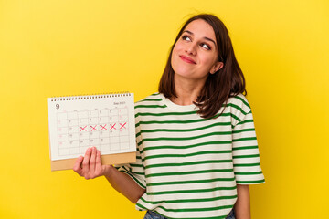 Young australian woman holding a calendar isolated on yellow background dreaming of achieving goals...