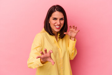 Young caucasian woman isolated on pink background showing claws imitating a cat, aggressive gesture.