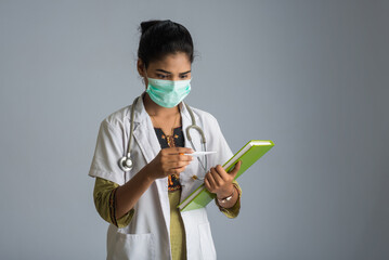 Beautiful young woman doctor with thermometer and report or book