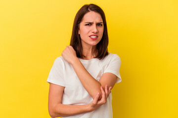 Fototapeta premium Young caucasian woman isolated on yellow background massaging elbow, suffering after a bad movement.