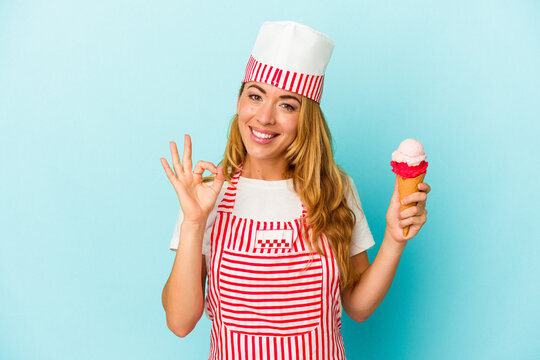 Caucasian ice cream maker woman holding an ice cream isolated on blue background cheerful and confident showing ok gesture.