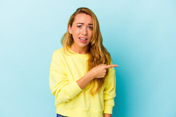 Caucasian woman isolated on blue background pointing to the side