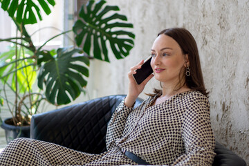 Happy cheerful young woman talking on the phone at home, smiling woman making answering call by...