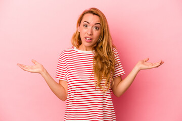 Caucasian blonde woman isolated on pink background doubting and shrugging shoulders in questioning...