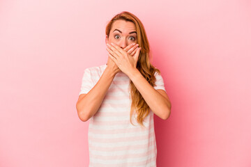 Caucasian blonde woman isolated on pink background shocked covering mouth with hands.