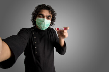 Young man taking a selfie with a test tube with blood sample for coronavirus or 2019-nCoV analyzing.