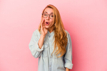 Caucasian blonde woman isolated on pink background is saying a secret hot braking news and looking aside