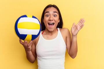 Young mixed race woman playing volleyball on the beach isolated on yellow background receiving a pleasant surprise, excited and raising hands.
