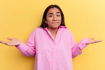 Young mixed race woman isolated on yellow background doubting and shrugging shoulders in questioning gesture.