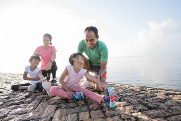 Fototapeta premium father and mother help their daughter to stretch the leg during exercising outdoor