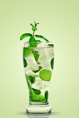A glass with a mojito on a green background. Cold ice drink.
