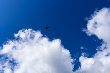 Silhouette of a helicopter against a blue sky with clouds