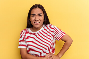 Young mixed race woman isolated on yellow background having a liver pain, stomach ache.