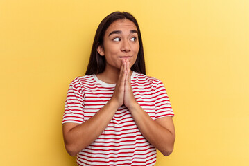 Young mixed race woman isolated on yellow background praying, showing devotion, religious person...
