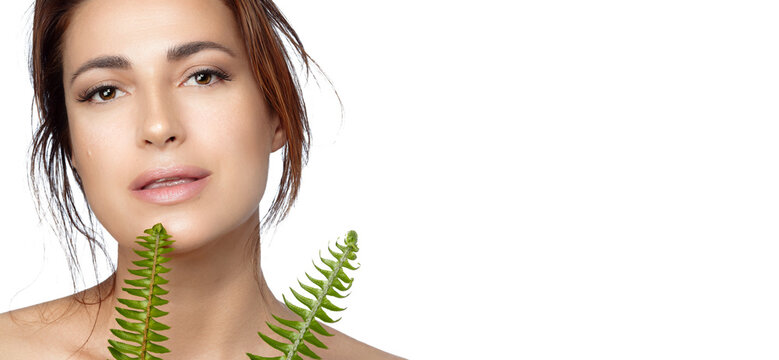 Natural beauty and skin care concept. Beautiful woman with perfect skin holding fern leaf near face