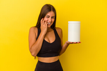 Young caucasian woman holding a protein bottle isolated on yellow background biting fingernails, nervous and very anxious.