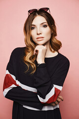 Close up portrait of a young model woman with bright makeup wearing trendy dress at the pink background