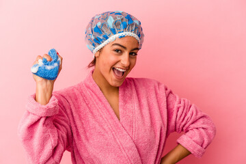 Young caucasian woman holding a sponge isolated on pink background