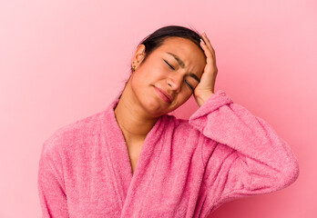 Young Venezuelan woman wearing a bathrobe isolated on pink background being shocked, she has...