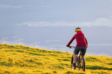 Woman riding mountain bike into the sunset. Beautiful golden summer light.