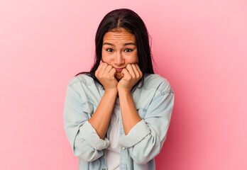 Young Venezuelan woman isolated on pink background biting fingernails, nervous and very anxious.