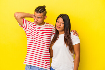 Fototapeta na wymiar Young latin couple isolated on yellow background touching back of head, thinking and making a choice.