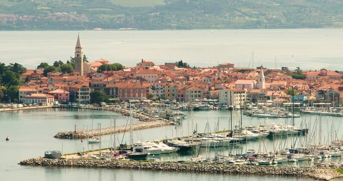 Elevated view of old town Izola in Slovenia. Adriatic Sea coast. Boats and yachts docket in marina. Panoramic static shot of Mediterranean settlement Isola. Sailboat leave the harbor. Static shot