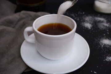 Cup of black coffee with sugar on a black background