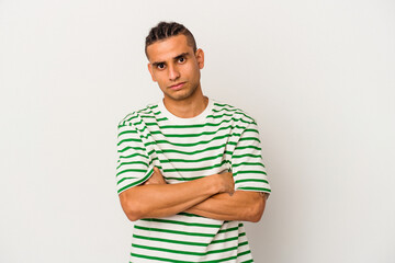 Young venezuelan man isolated on white background frowning face in displeasure, keeps arms folded.