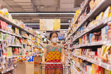 Asian sister in protective mask teaching younger brother homework.