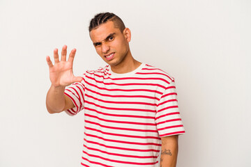 Naklejka premium Young venezuelan man isolated on white background showing claws imitating a cat, aggressive gesture.