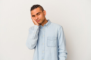 Young venezuelan man isolated on white background tired and very sleepy keeping hand on head.